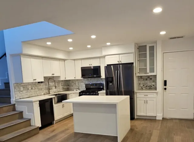A cleaned kitchen with a white island, wiped cabinet fronts and a clear countertop