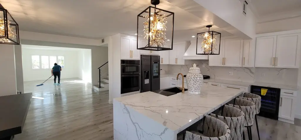 A crew member mopping the floor of a large open kitchen and living area