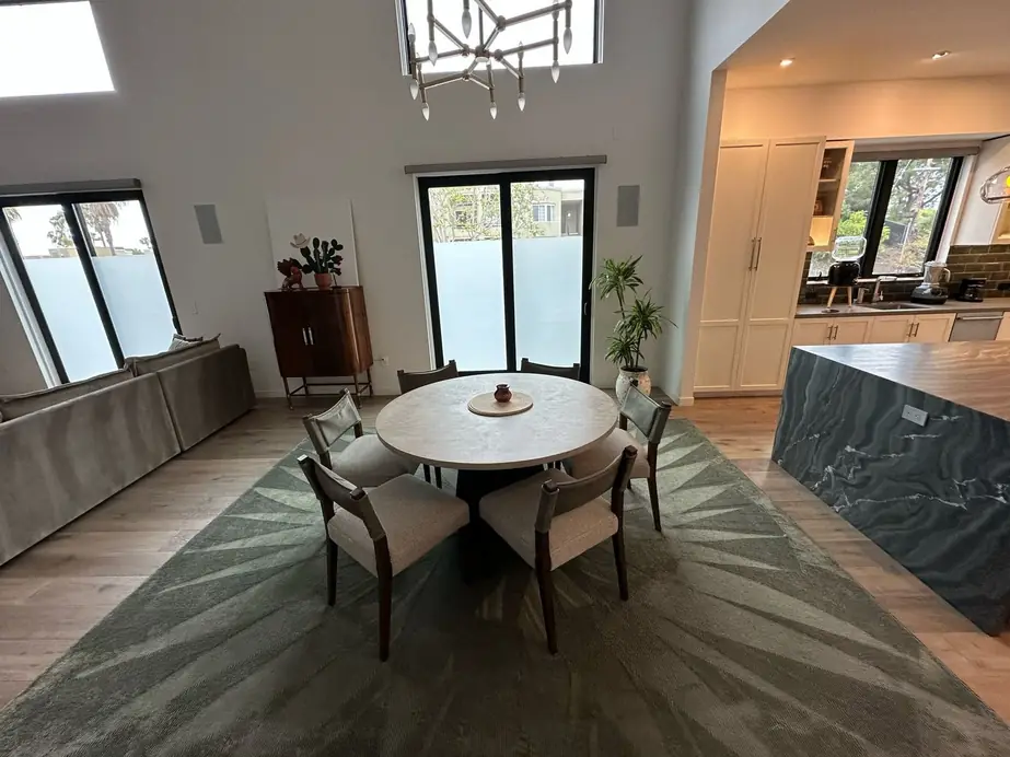 A vaulted living and dining room with tall windows, cleaned and set