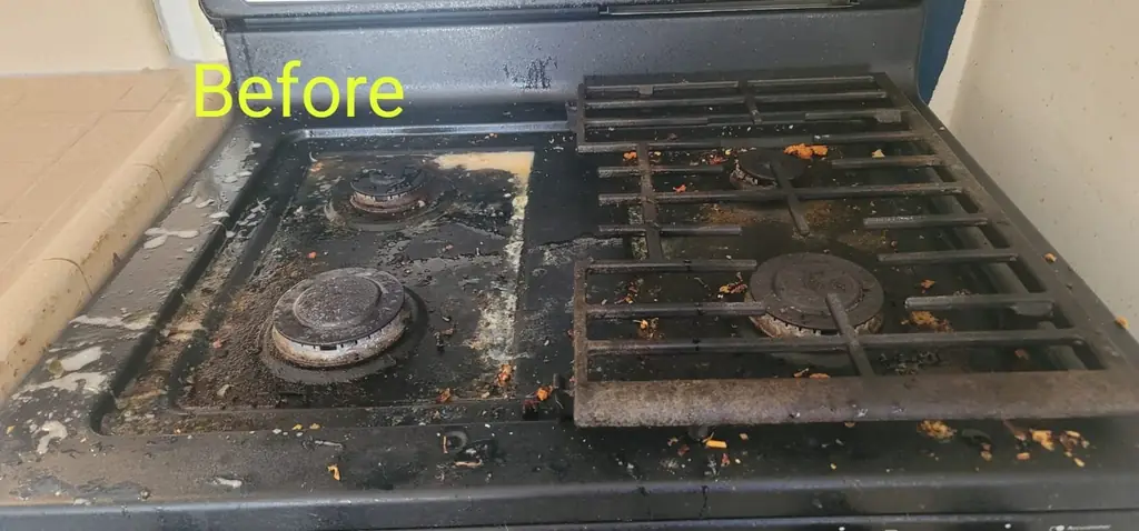 A gas stovetop with greasy burners and grates before cleaning